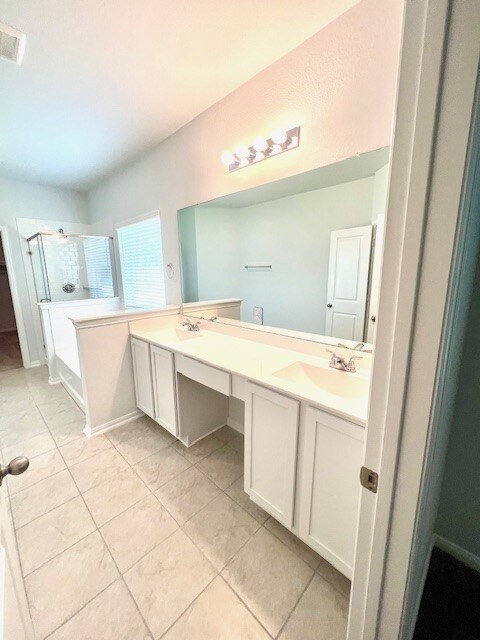 bathroom with a stall shower, visible vents, a sink, and double vanity