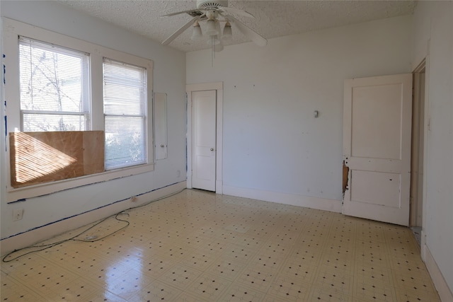 unfurnished room with ceiling fan, light tile patterned floors, and a textured ceiling