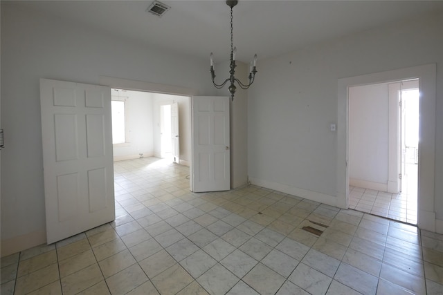 spare room with light tile patterned floors and an inviting chandelier