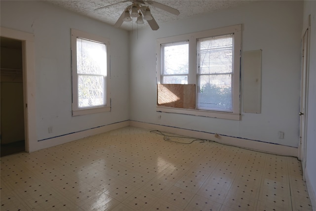 tiled empty room with ceiling fan, a textured ceiling, and a wealth of natural light