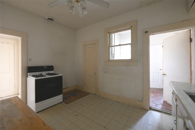 kitchen with ceiling fan, tile countertops, light tile patterned floors, and white range with gas cooktop