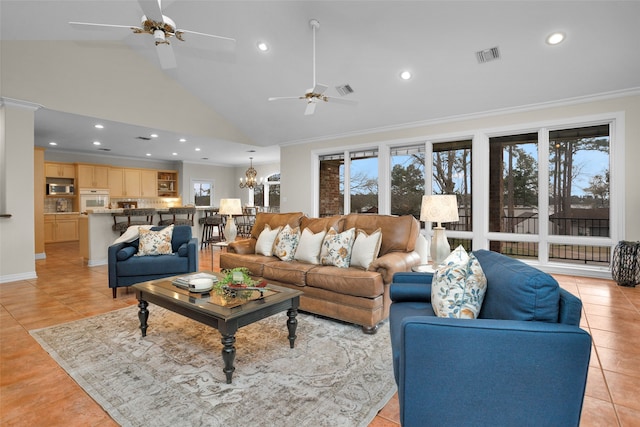 tiled living room with ceiling fan with notable chandelier, high vaulted ceiling, and ornamental molding