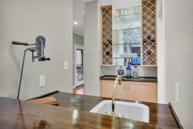 bar featuring light brown cabinetry, sink, and ornamental molding