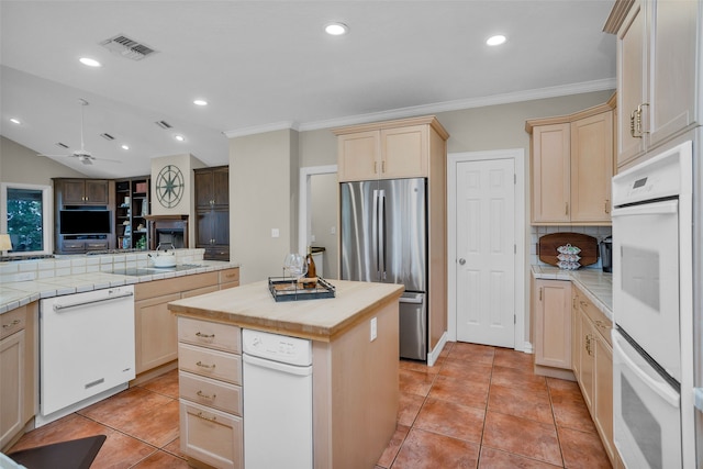 kitchen with kitchen peninsula, ceiling fan, white appliances, a center island, and decorative backsplash