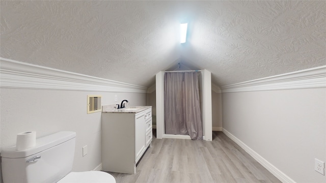 bathroom featuring vanity, lofted ceiling, a textured ceiling, toilet, and hardwood / wood-style flooring