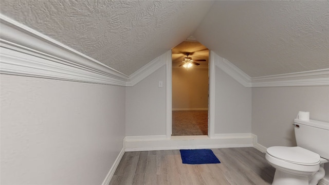 bathroom featuring hardwood / wood-style floors, ceiling fan, vaulted ceiling, a textured ceiling, and toilet