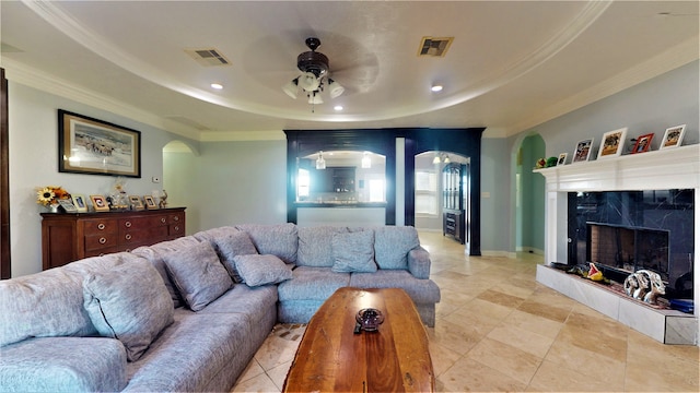 living room with a raised ceiling, ceiling fan, light tile floors, and a fireplace