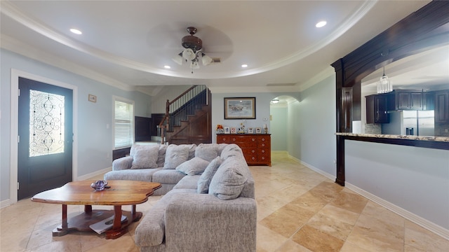 living room featuring ornamental molding, light tile flooring, ceiling fan, and a tray ceiling