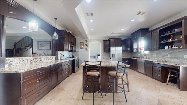 kitchen with hanging light fixtures, tasteful backsplash, stainless steel appliances, and dark brown cabinets