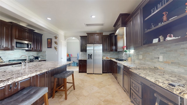 kitchen with light tile floors, tasteful backsplash, a breakfast bar area, appliances with stainless steel finishes, and sink