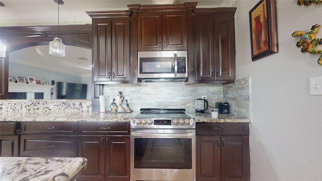 kitchen with hanging light fixtures, appliances with stainless steel finishes, light stone counters, and tasteful backsplash