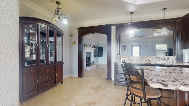 kitchen featuring light tile floors, ceiling fan with notable chandelier, a kitchen breakfast bar, decorative light fixtures, and light stone countertops