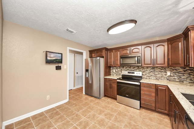 kitchen featuring decorative backsplash, light tile patterned floors, light stone countertops, a textured ceiling, and appliances with stainless steel finishes