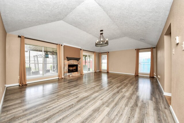 unfurnished living room featuring a fireplace, wood-type flooring, a chandelier, and lofted ceiling