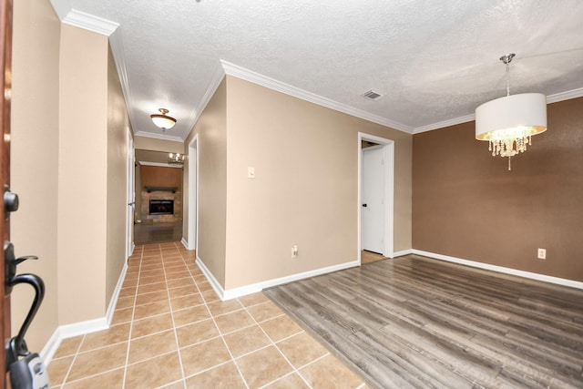 tiled spare room featuring a textured ceiling, crown molding, and a notable chandelier