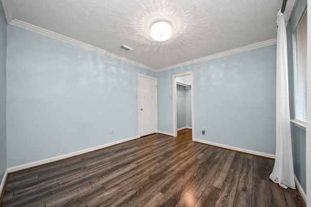 empty room featuring dark wood-type flooring, a textured ceiling, and ornamental molding