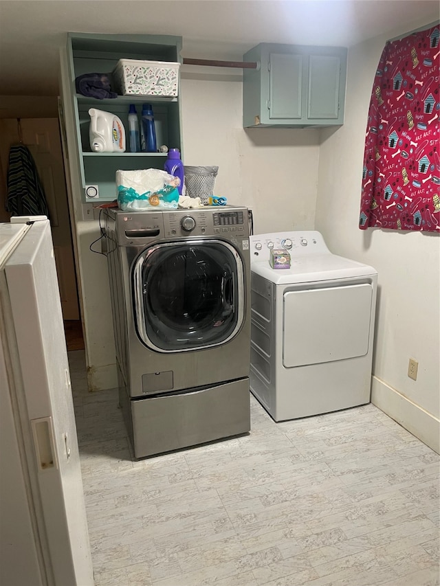 laundry area with light hardwood / wood-style floors, cabinets, and washer and clothes dryer