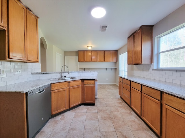 kitchen with stainless steel dishwasher, light tile flooring, light stone countertops, tasteful backsplash, and sink