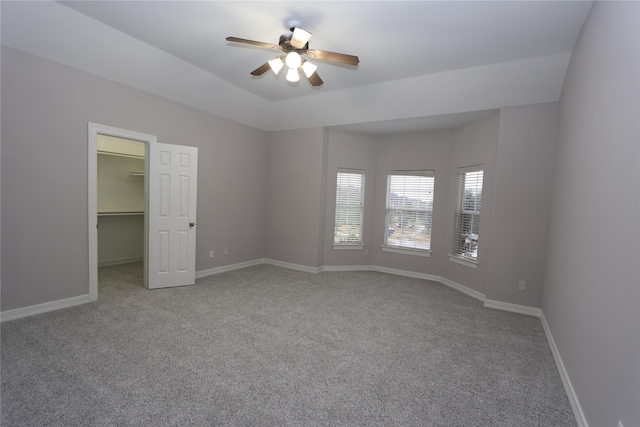 unfurnished bedroom featuring carpet floors, a spacious closet, ceiling fan, and a closet