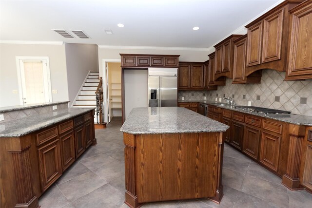 kitchen with dark stone counters, tasteful backsplash, a center island, appliances with stainless steel finishes, and tile patterned flooring