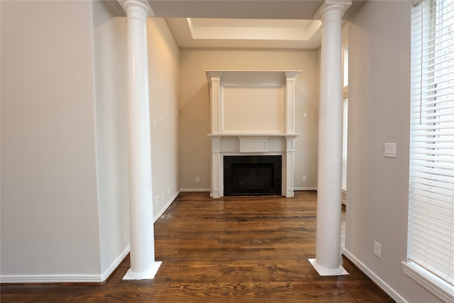 corridor featuring dark hardwood / wood-style floors, ornate columns, and a raised ceiling