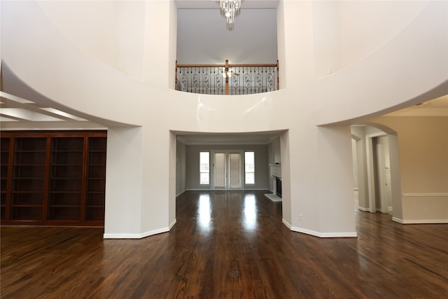 foyer featuring dark wood-type flooring, a towering ceiling, french doors, and a chandelier