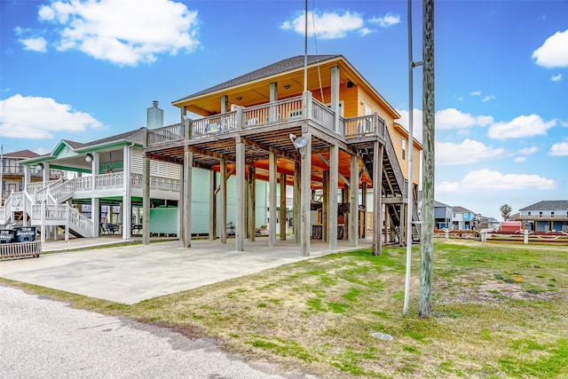 back of house with a deck, a patio area, and a lawn