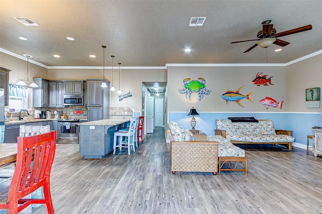 living room with light hardwood / wood-style flooring, ceiling fan, sink, and ornamental molding