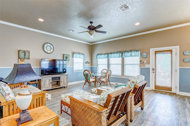 living room featuring crown molding, a textured ceiling, ceiling fan, and light hardwood / wood-style flooring