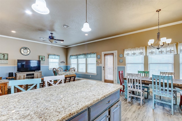 kitchen featuring decorative light fixtures, light stone counters, crown molding, light hardwood / wood-style flooring, and ceiling fan with notable chandelier