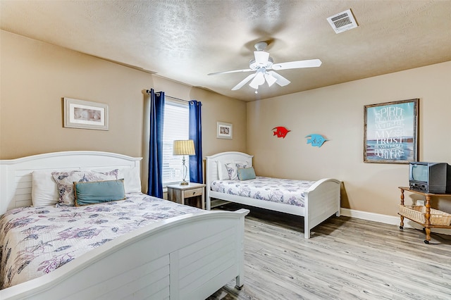 bedroom featuring a textured ceiling, ceiling fan, and light wood-type flooring