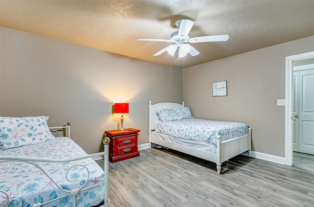 bedroom with ceiling fan, light hardwood / wood-style floors, and a textured ceiling