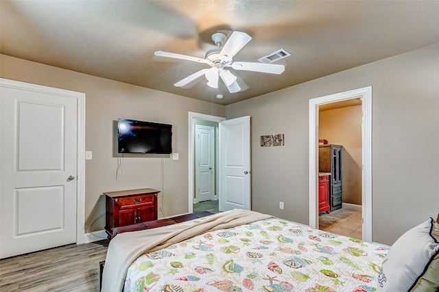 bedroom with ceiling fan, ensuite bathroom, and light hardwood / wood-style flooring