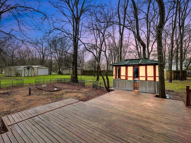 deck at dusk with an outdoor structure and a yard