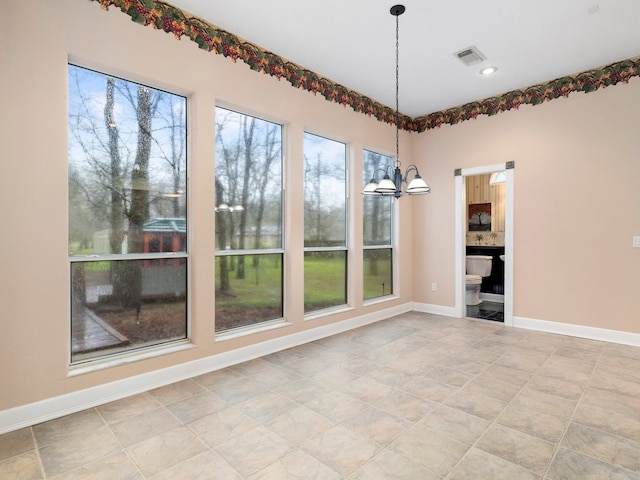 tiled empty room featuring a chandelier and a healthy amount of sunlight