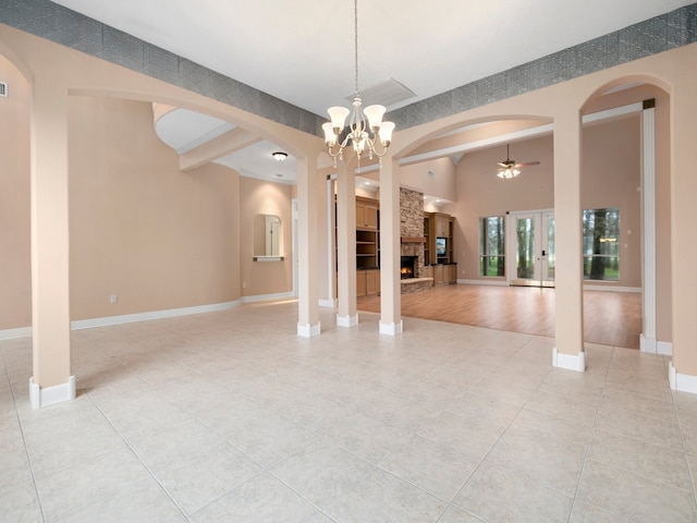 empty room featuring light tile floors, ceiling fan with notable chandelier, and a fireplace