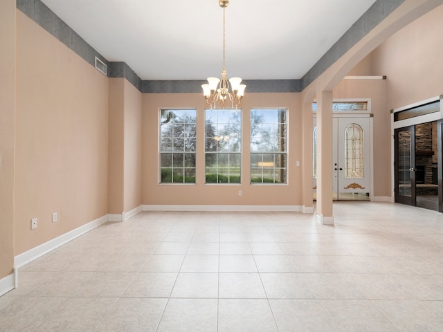 spare room with light tile flooring and a chandelier