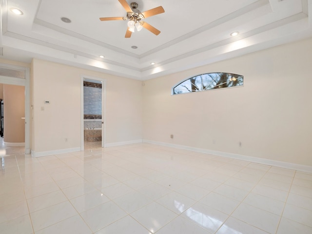 spare room with light tile flooring, ceiling fan, and a tray ceiling