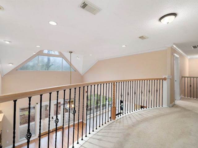 hall featuring light colored carpet, ornamental molding, and vaulted ceiling