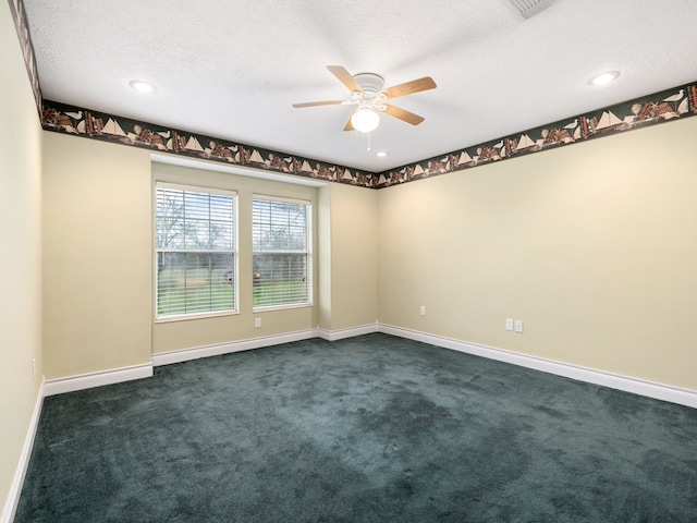 empty room with a textured ceiling, dark colored carpet, and ceiling fan