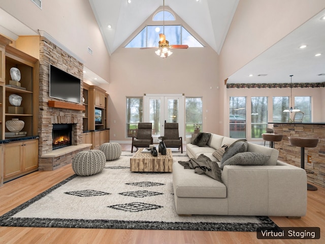 living room with high vaulted ceiling, light hardwood / wood-style floors, french doors, and a fireplace