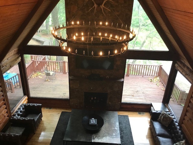 living room with high vaulted ceiling, a fireplace, a chandelier, and hardwood / wood-style flooring