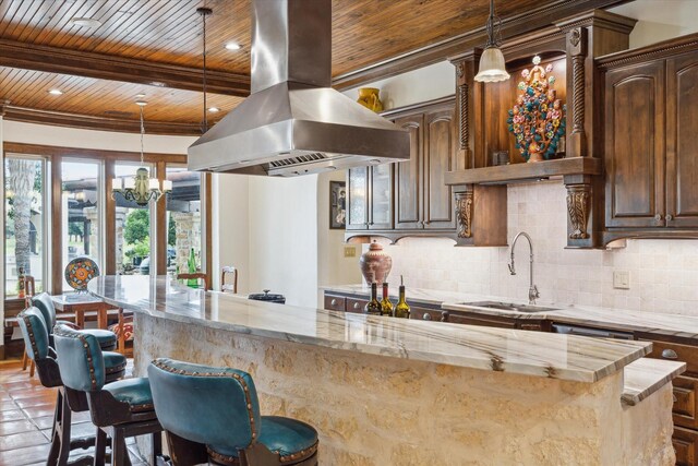 kitchen with dark brown cabinets, island range hood, sink, and a breakfast bar area