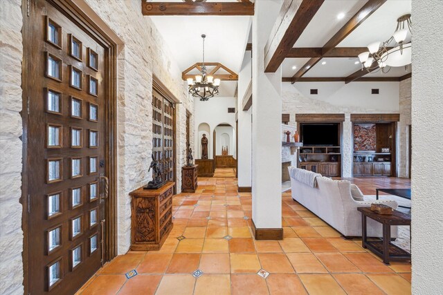 tiled entryway featuring beamed ceiling, a notable chandelier, and a high ceiling