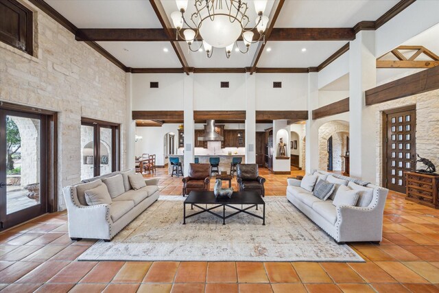 living room with a chandelier, beam ceiling, and a towering ceiling