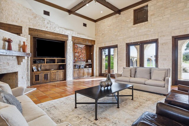 tiled living room with a high ceiling, a stone fireplace, crown molding, and beam ceiling