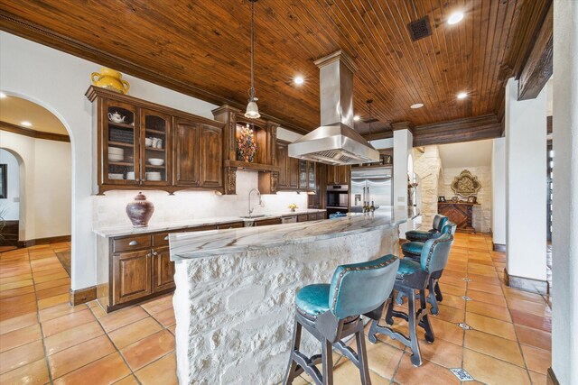 kitchen featuring sink, built in refrigerator, light stone counters, wood ceiling, and island exhaust hood