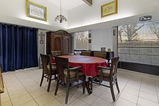 tiled dining room with an inviting chandelier, a towering ceiling, and beamed ceiling