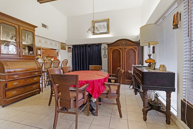 dining space with high vaulted ceiling, light tile flooring, and beamed ceiling