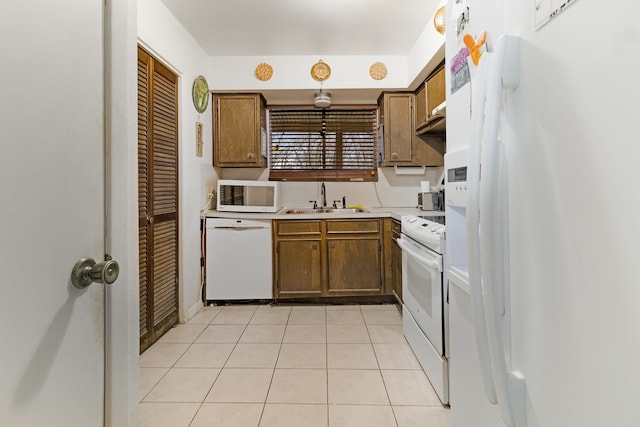 kitchen with white appliances, sink, and light tile flooring